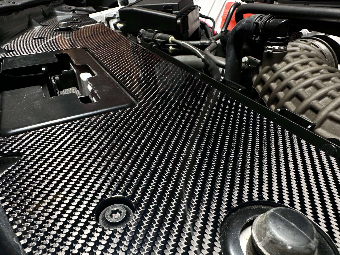 
                  
                    Gloss 2x2 twill carbon fiber weave – Camaro radiator cover detail engine bay
                  
                