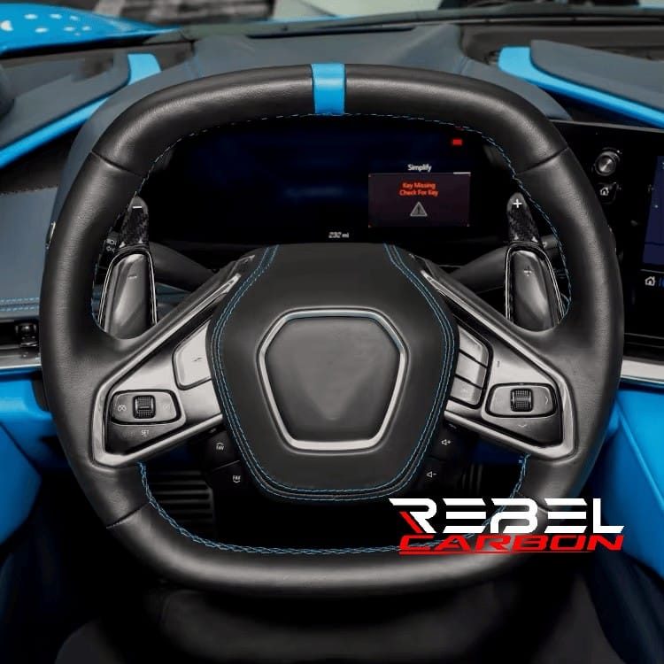 Rebel Carbon Fiber paddle shifter extensions installed on a C8 Corvette steering wheel with high-gloss carbon finish