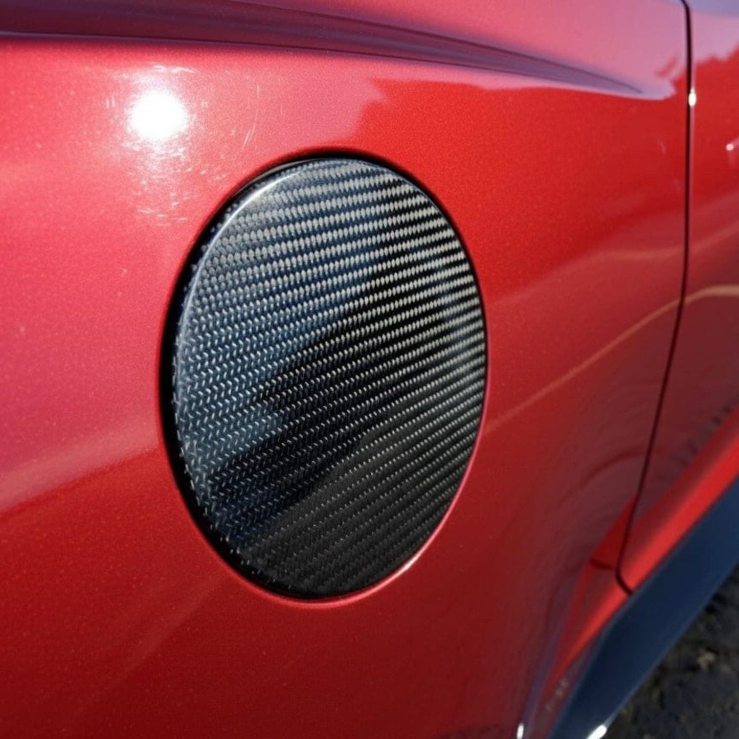 Rebel Carbon Fiber fuel door cover installed on a red 6th Gen Chevrolet Camaro with a glossy 2x2 twill weave finish.